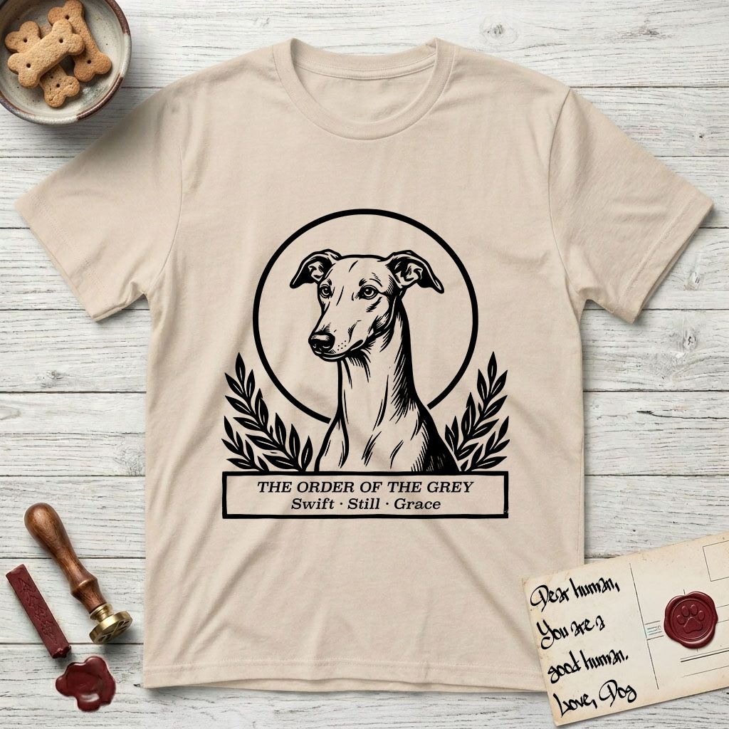 Holy Orders Greyhound T-Shirt flat lay in Sand, featuring a bold black-and-white linocut saint-medallion portrait of a Greyhound.