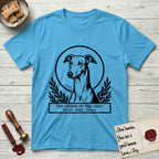 Holy Orders Greyhound T-Shirt flat lay in Sky, featuring a bold black-and-white linocut saint-medallion portrait of a Greyhound.