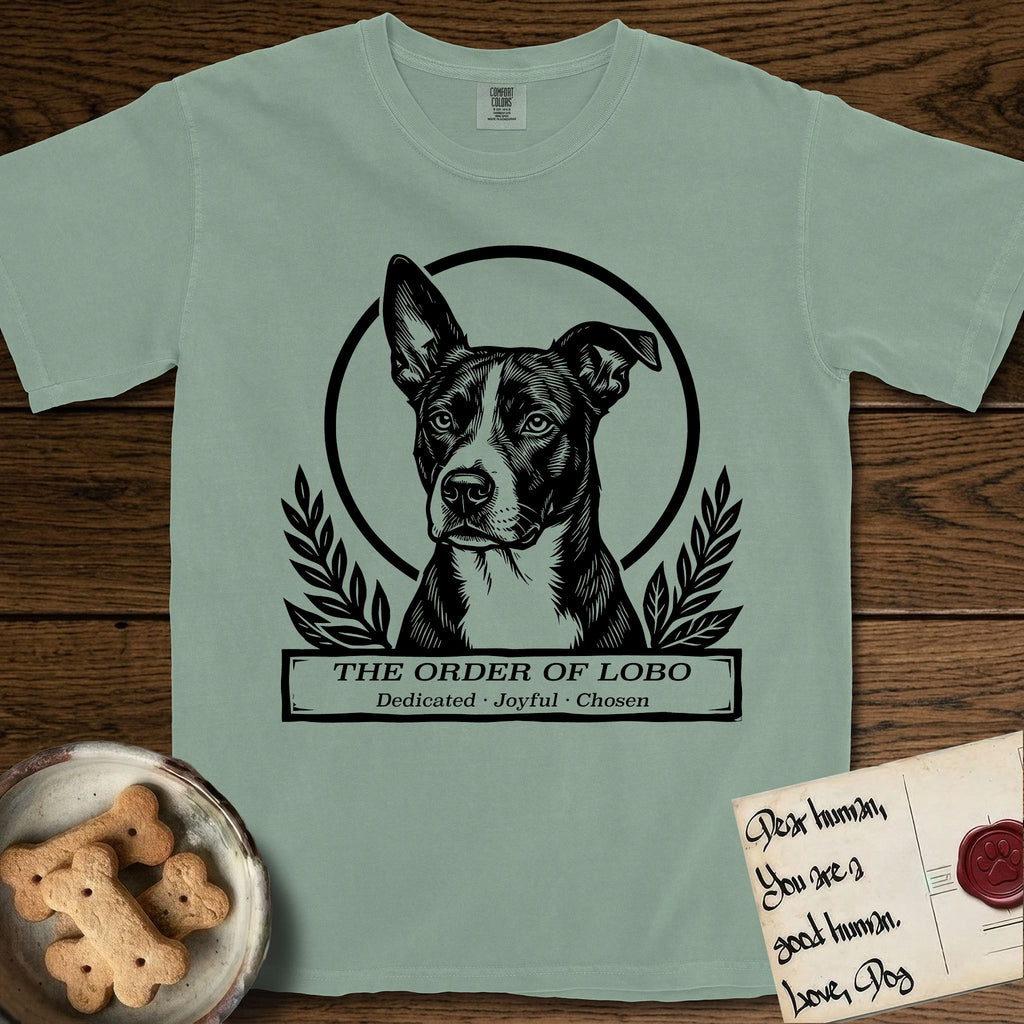 Holy Orders Lobo T-Shirt flat lay in Bay, featuring a bold black-and-white linocut saint-medallion portrait of Lobo, an Australian Cattle Dog and Pitbull mix with a white facial blaze.