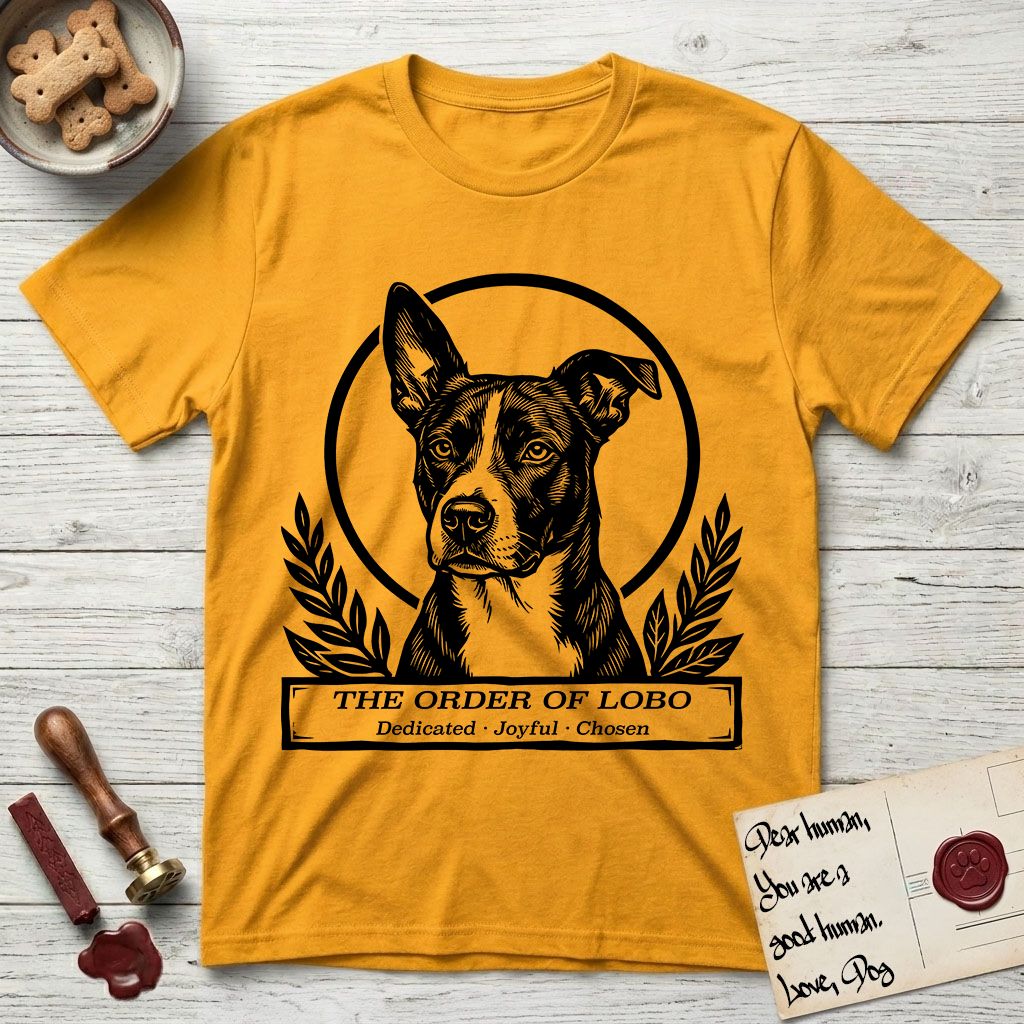 Holy Orders Lobo T-Shirt flat lay in Gold, featuring a bold black-and-white linocut saint-medallion portrait of Lobo, an Australian Cattle Dog and Pitbull mix with a white facial blaze.