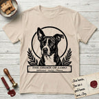 Holy Orders Lobo T-Shirt flat lay in Sand, featuring a bold black-and-white linocut saint-medallion portrait of Lobo, an Australian Cattle Dog and Pitbull mix with a white facial blaze.