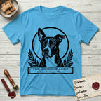 Holy Orders Lobo T-Shirt flat lay in Sky, featuring a bold black-and-white linocut saint-medallion portrait of Lobo, an Australian Cattle Dog and Pitbull mix with a white facial blaze.