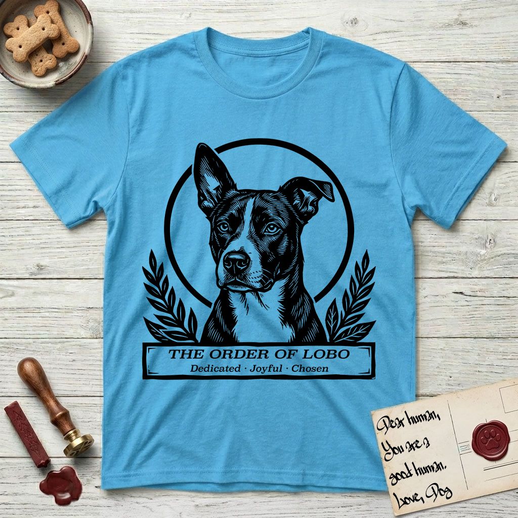 Holy Orders Lobo T-Shirt flat lay in Sky, featuring a bold black-and-white linocut saint-medallion portrait of Lobo, an Australian Cattle Dog and Pitbull mix with a white facial blaze.