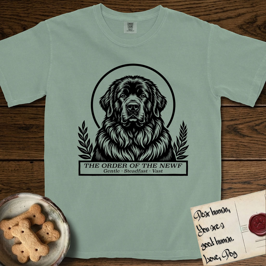 Holy Orders Newfoundland T-Shirt flat lay in Bay, featuring a bold black-and-white linocut saint-medallion portrait of a Newfoundland.