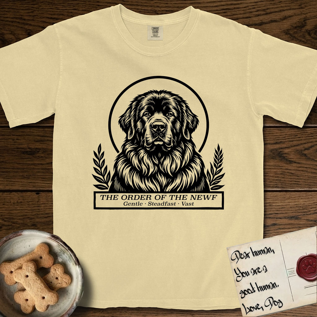 Holy Orders Newfoundland T-Shirt flat lay in Butter, featuring a bold black-and-white linocut saint-medallion portrait of a Newfoundland.
