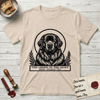 Holy Orders Newfoundland T-Shirt flat lay in Sand, featuring a bold black-and-white linocut saint-medallion portrait of a Newfoundland.