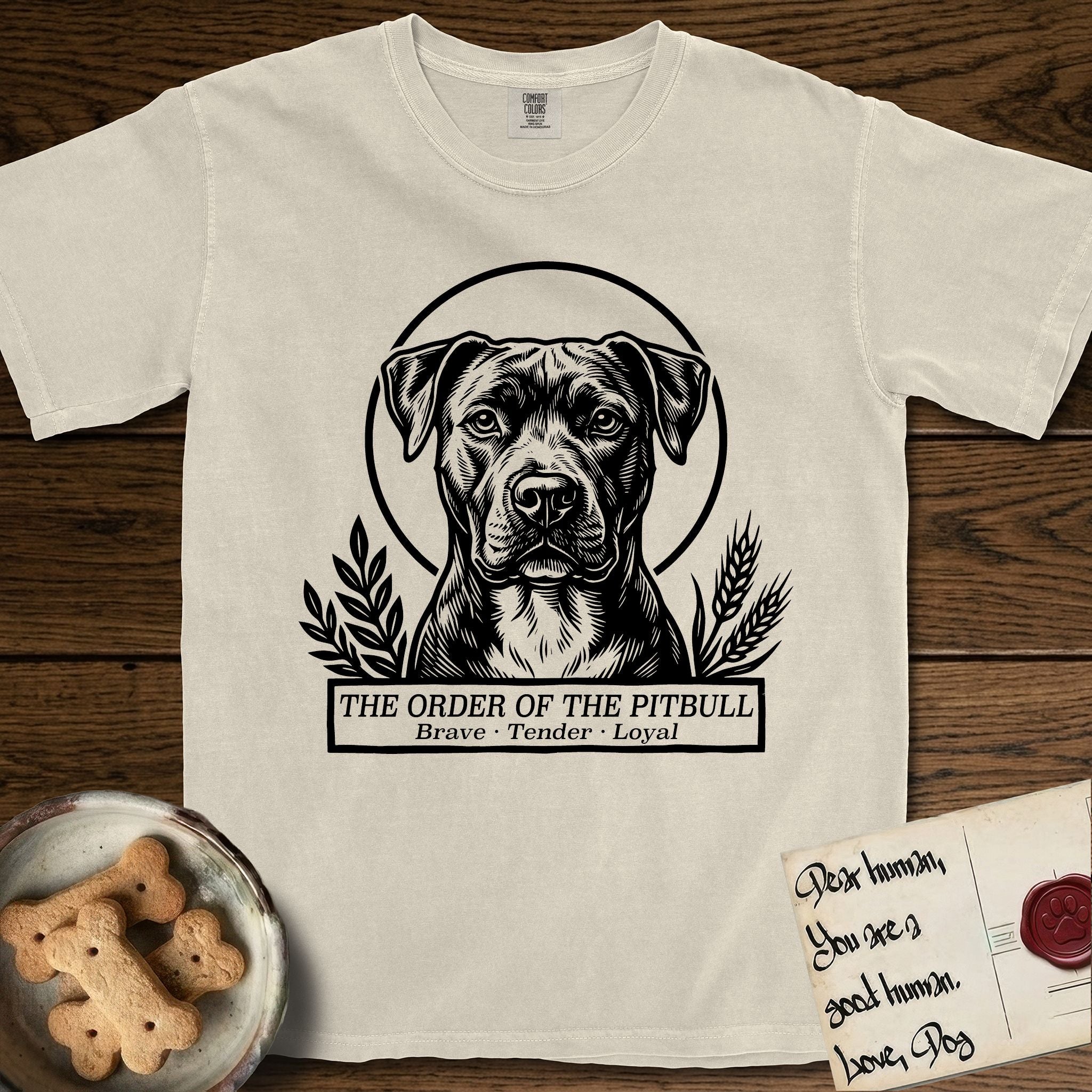 Holy Orders Pitbull T-Shirt flat lay in Ivory, featuring a bold black-and-white linocut saint-medallion portrait of a Pitbull.