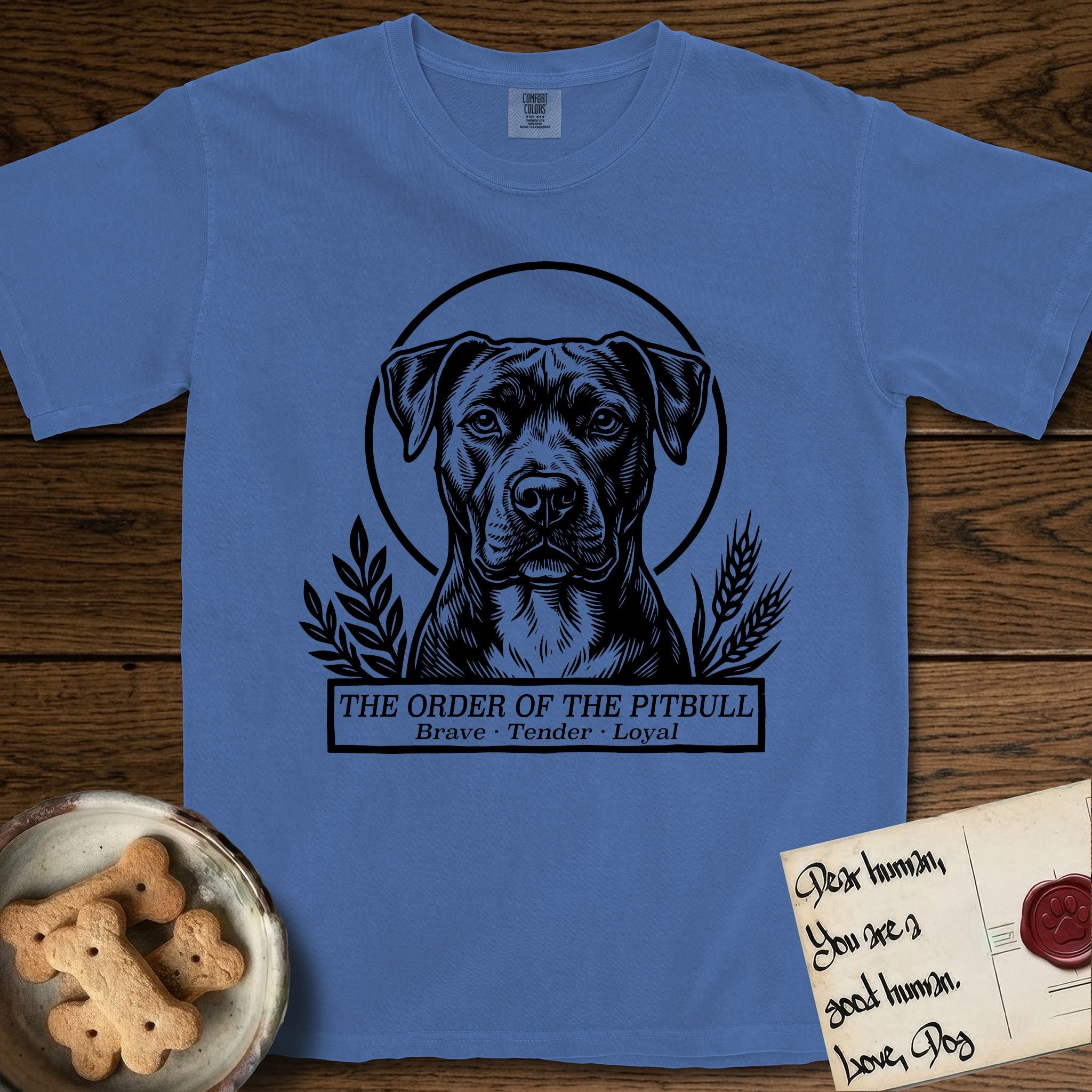 Holy Orders Pitbull T-Shirt flat lay in Mystic Blue, featuring a bold black-and-white linocut saint-medallion portrait of a Pitbull.