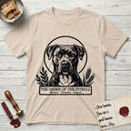 Holy Orders Pitbull T-Shirt flat lay in Sand, featuring a bold black-and-white linocut saint-medallion portrait of a Pitbull.