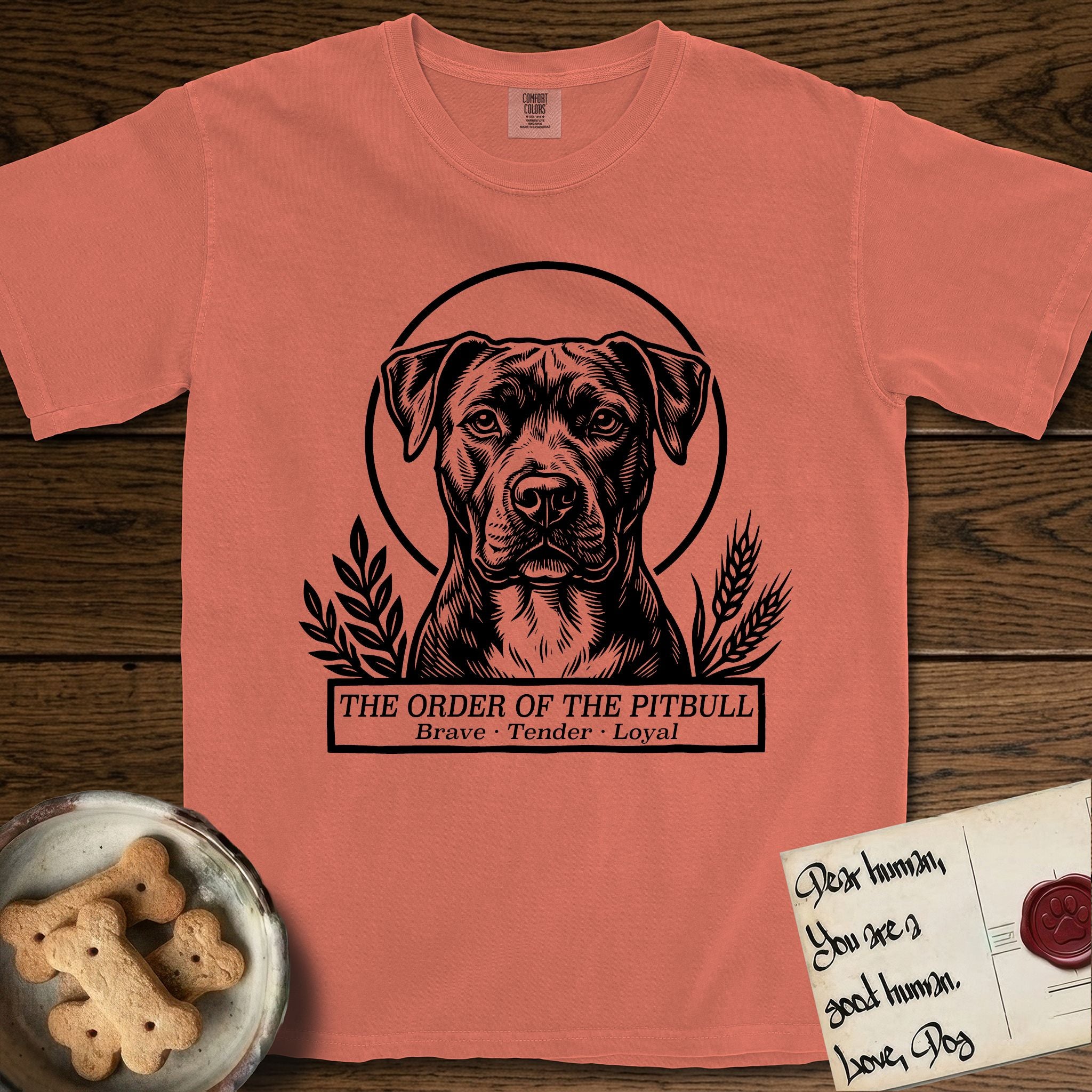 Holy Orders Pitbull T-Shirt flat lay in Terracotta, featuring a bold black-and-white linocut saint-medallion portrait of a Pitbull.