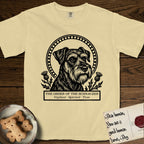 Holy Orders Schnauzer T-Shirt flat lay in Butter, featuring a bold black-and-white linocut saint-medallion portrait of a Schnauzer.