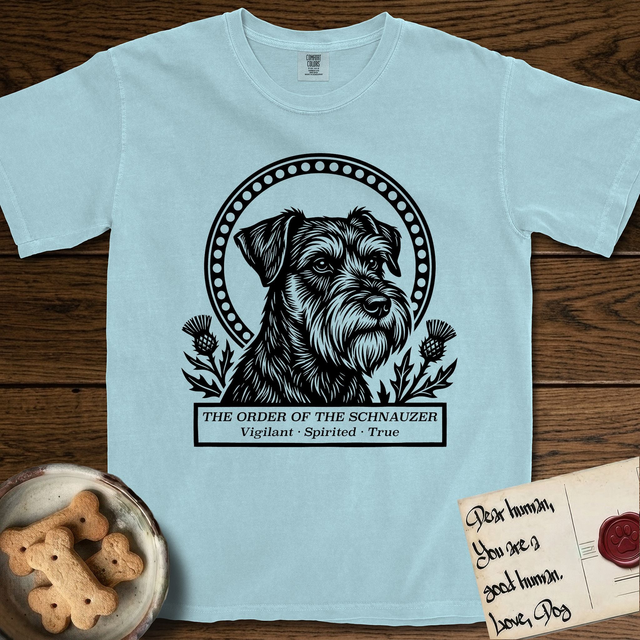 Holy Orders Schnauzer T-Shirt flat lay in Chambray, featuring a bold black-and-white linocut saint-medallion portrait of a Schnauzer.