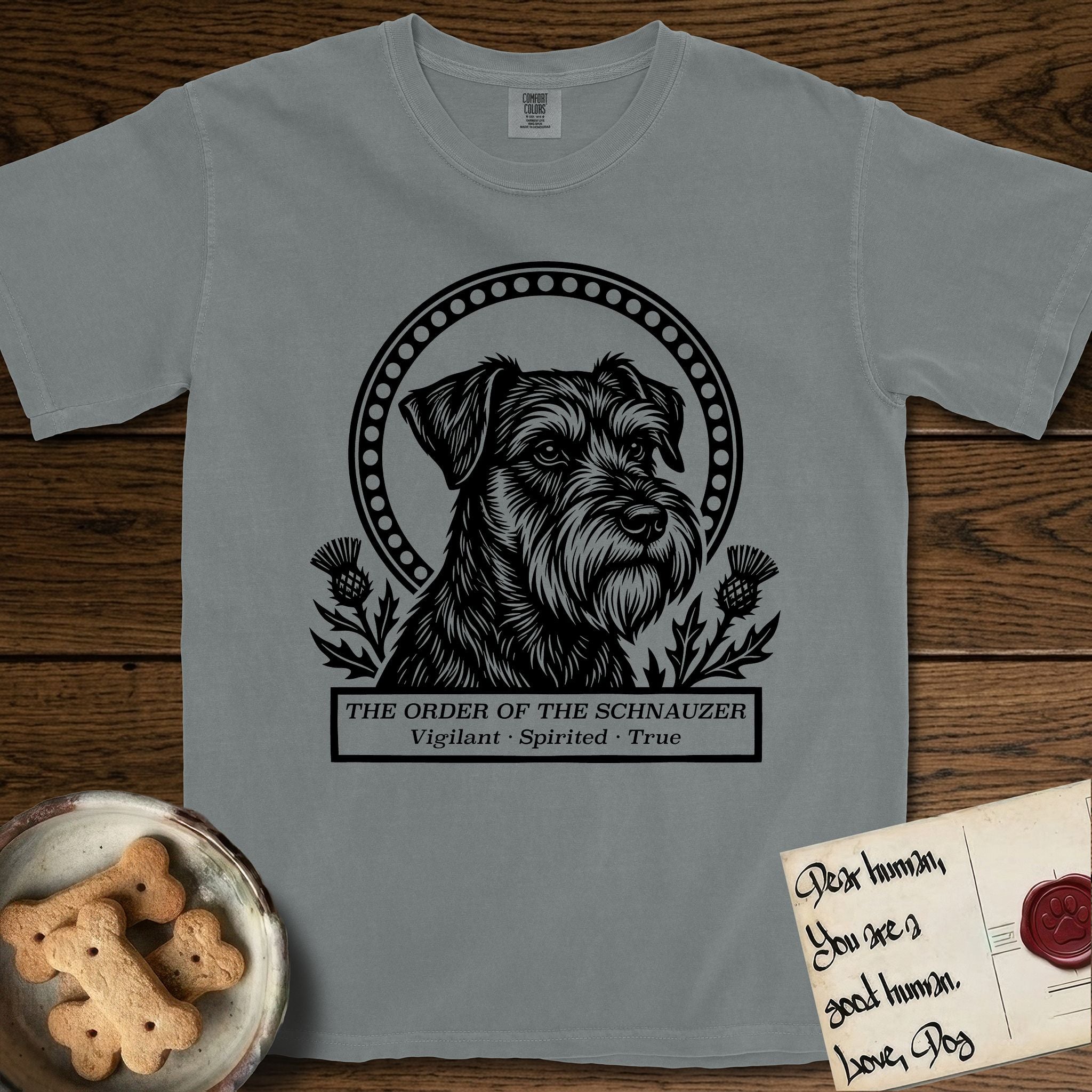 Holy Orders Schnauzer T-Shirt flat lay in Granite, featuring a bold black-and-white linocut saint-medallion portrait of a Schnauzer.