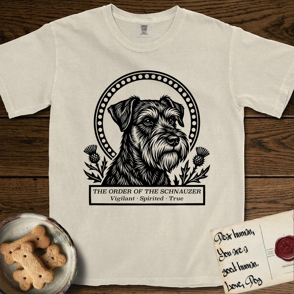 Holy Orders Schnauzer T-Shirt flat lay in Ivory, featuring a bold black-and-white linocut saint-medallion portrait of a Schnauzer.
