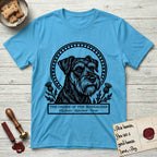 Holy Orders Schnauzer T-Shirt flat lay in Sky, featuring a bold black-and-white linocut saint-medallion portrait of a Schnauzer.