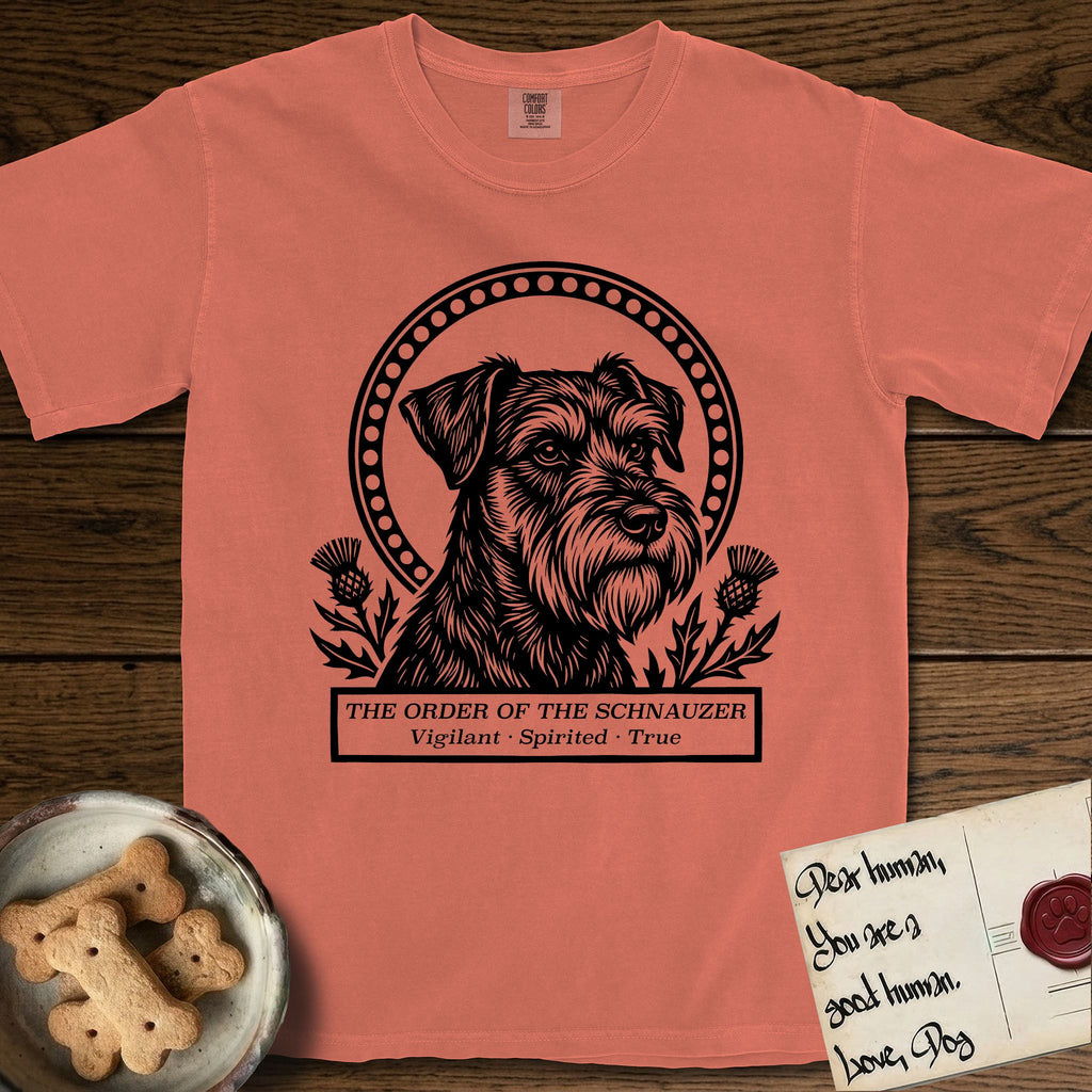 Holy Orders Schnauzer T-Shirt flat lay in Terracotta, featuring a bold black-and-white linocut saint-medallion portrait of a Schnauzer.