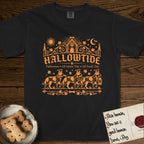 Hallowtide Australian Cattle Dog T-Shirt flat lay in Black, featuring Orange one-color gothic illustration of three haloed speckled Australian Cattle Dogs walking in procession carrying a skeleton key, a scary jack-o'-lantern, and an iron lantern, under the blackletter headline HALLOWTIDE.