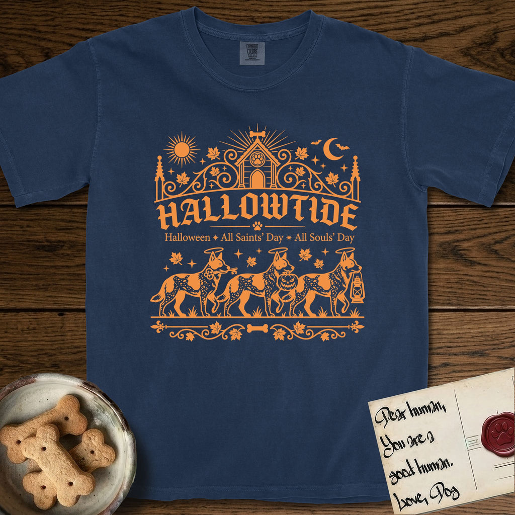 Hallowtide Australian Cattle Dog T-Shirt flat lay in True Navy, featuring Orange one-color gothic illustration of three haloed speckled Australian Cattle Dogs walking in procession carrying a skeleton key, a scary jack-o'-lantern, and an iron lantern, under the blackletter headline HALLOWTIDE.