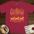 Hallowtide Black Lab T-Shirt flat lay in Chili, featuring Orange one-color gothic illustration of three haloed Black Labs walking in procession carrying a skeleton key, a scary jack-o'-lantern, and an iron lantern, under the blackletter headline HALLOWTIDE.