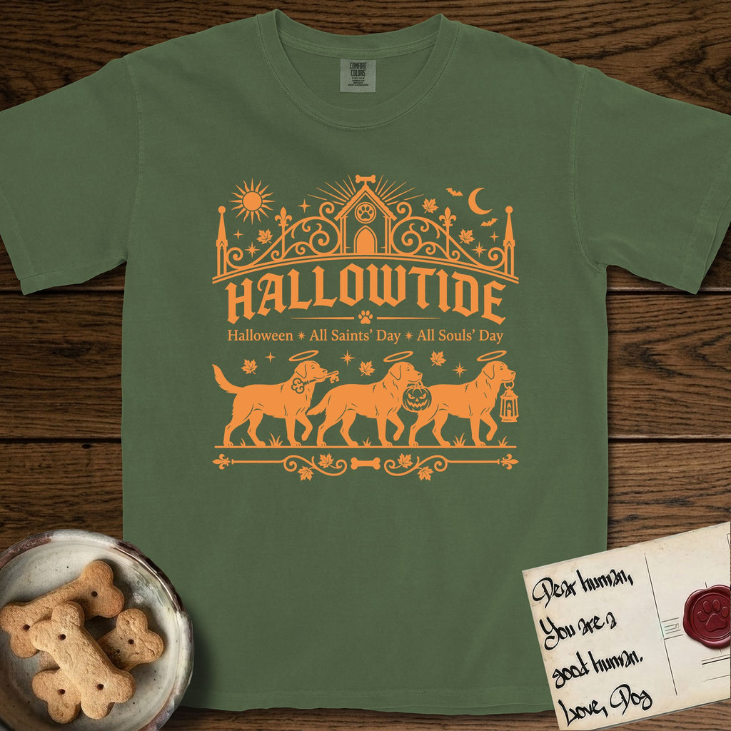 Hallowtide Black Lab T-Shirt flat lay in Moss, featuring Orange one-color gothic illustration of three haloed Black Labs walking in procession carrying a skeleton key, a scary jack-o'-lantern, and an iron lantern, under the blackletter headline HALLOWTIDE.
