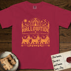 Hallowtide Cairn Terrier T-Shirt flat lay in Chili, featuring Orange one-color gothic illustration of three haloed shaggy Cairn Terriers walking in procession carrying a skeleton key, a scary jack-o'-lantern, and an iron lantern, under the blackletter headline HALLOWTIDE.