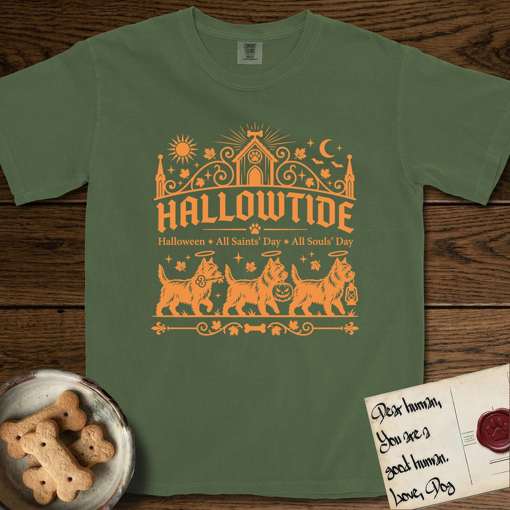 Hallowtide Cairn Terrier T-Shirt flat lay in Moss, featuring Orange one-color gothic illustration of three haloed shaggy Cairn Terriers walking in procession carrying a skeleton key, a scary jack-o'-lantern, and an iron lantern, under the blackletter headline HALLOWTIDE.