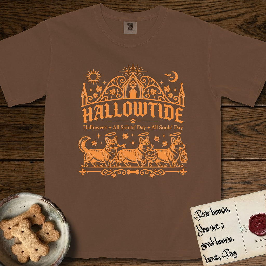 Hallowtide Corgi T-Shirt flat lay in Espresso, featuring Orange one-color gothic illustration of three haloed Corgis walking in procession carrying a skeleton key, a scary jack-o'-lantern, and an iron lantern, under the blackletter headline HALLOWTIDE.