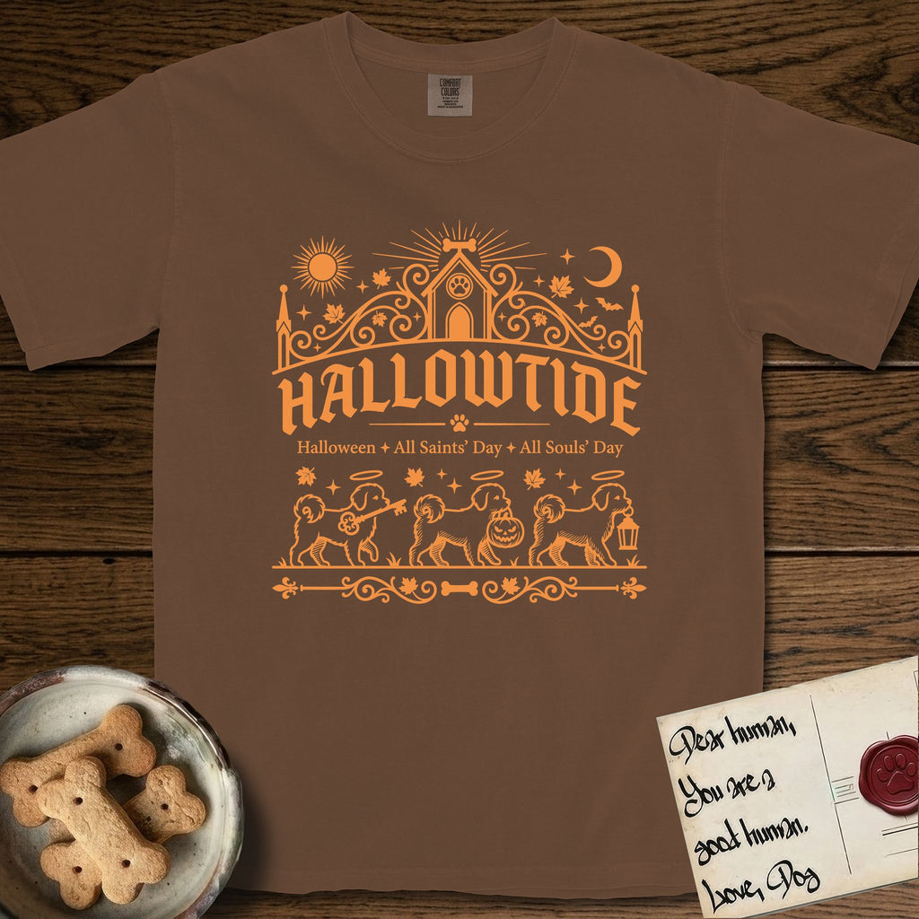 Hallowtide Maltese T-Shirt flat lay in Espresso, featuring Orange one-color gothic illustration of three haloed Maltese walking in procession carrying a skeleton key, a scary jack-o'-lantern, and an iron lantern, under the blackletter headline HALLOWTIDE.