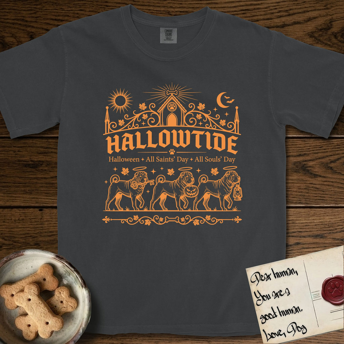 Hallowtide Shar-Pei T-Shirt flat lay in Graphite, featuring Orange one-color gothic illustration of three haloed wrinkled Shar-Peis walking in procession carrying a skeleton key, a scary jack-o'-lantern, and an iron lantern, under the blackletter headline HALLOWTIDE.