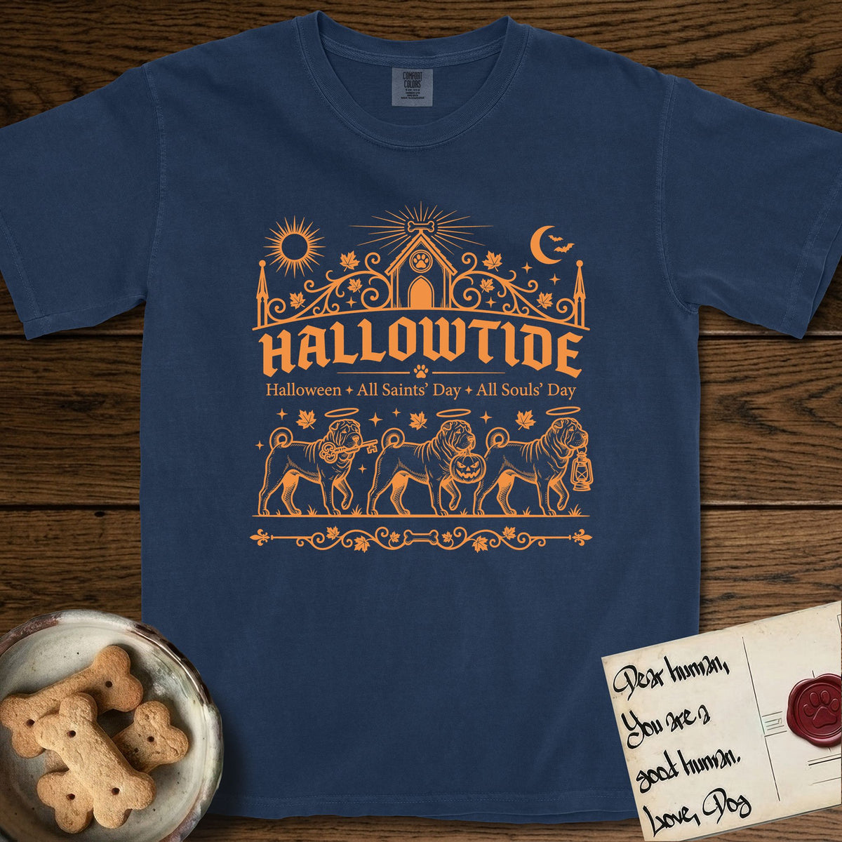 Hallowtide Shar-Pei T-Shirt flat lay in True Navy, featuring Orange one-color gothic illustration of three haloed wrinkled Shar-Peis walking in procession carrying a skeleton key, a scary jack-o'-lantern, and an iron lantern, under the blackletter headline HALLOWTIDE.