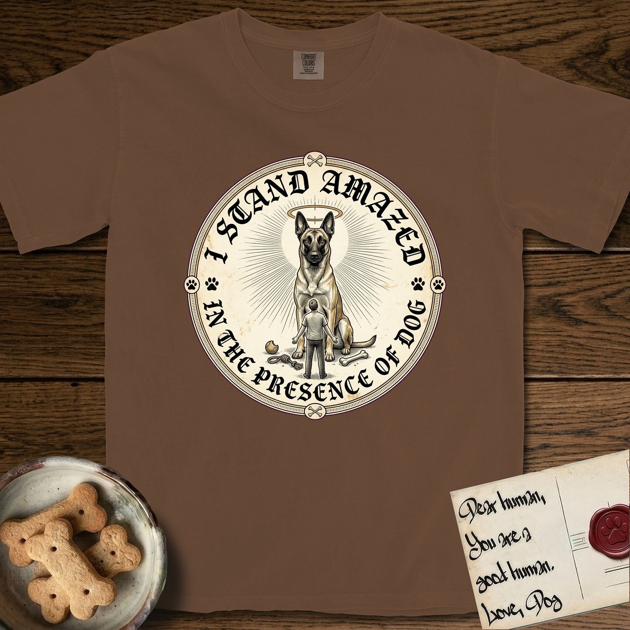 I Stand Amazed in the Presence Belgian Malinois T-Shirt flat lay in Espresso, featuring a vintage engraving medallion of a haloed Belgian Malinois with a small devoted human gazing up from below.