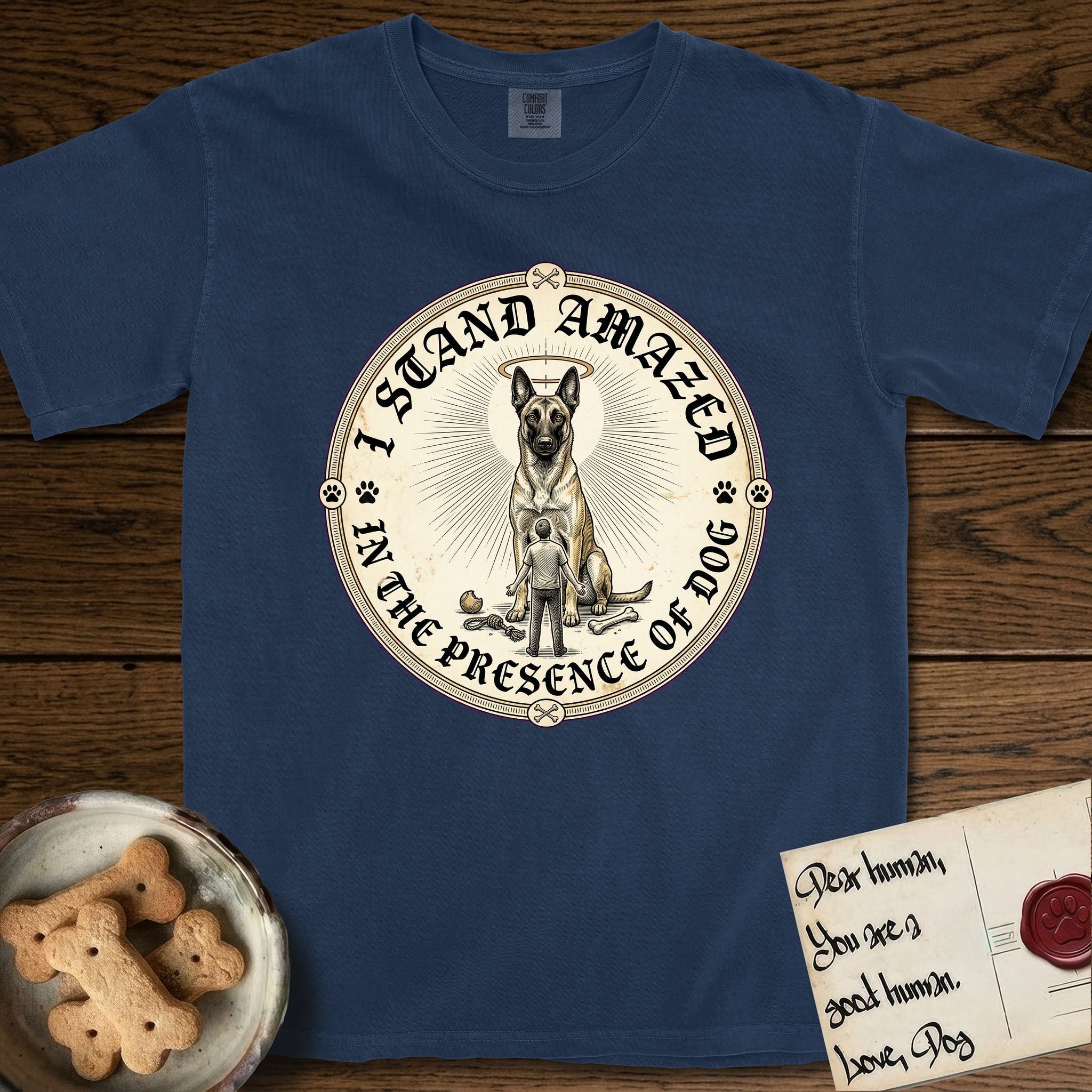 I Stand Amazed in the Presence Belgian Malinois T-Shirt flat lay in True Navy, featuring a vintage engraving medallion of a haloed Belgian Malinois with a small devoted human gazing up from below.