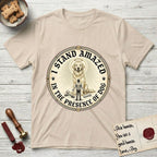 I Stand Amazed in the Presence Golden Retriever T-Shirt flat lay in Sand, featuring a vintage engraving medallion of a haloed Golden Retriever with a small devoted human gazing up from below.