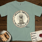 I Stand Amazed in the Presence Goldendoodle T-Shirt flat lay in Bay, featuring a vintage engraving medallion of a haloed Goldendoodle with a small devoted human gazing up from below.