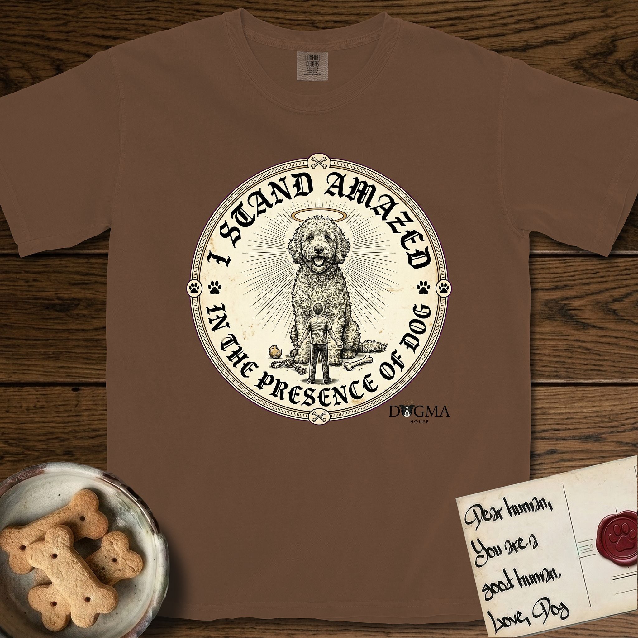 I Stand Amazed in the Presence Goldendoodle T-Shirt flat lay in Espresso, featuring a vintage engraving medallion of a haloed Goldendoodle with a small devoted human gazing up from below.