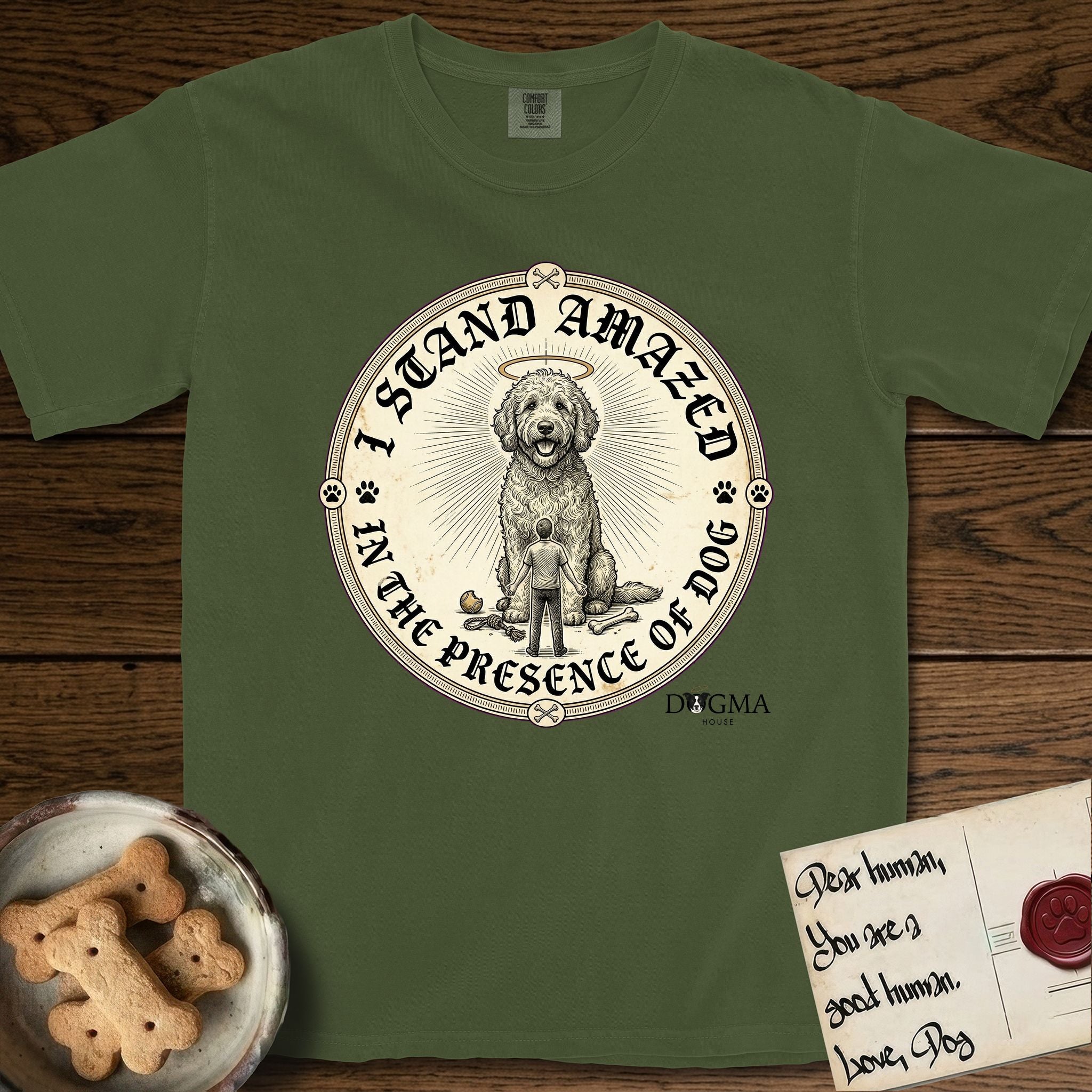 I Stand Amazed in the Presence Goldendoodle T-Shirt flat lay in Hemp, featuring a vintage engraving medallion of a haloed Goldendoodle with a small devoted human gazing up from below.