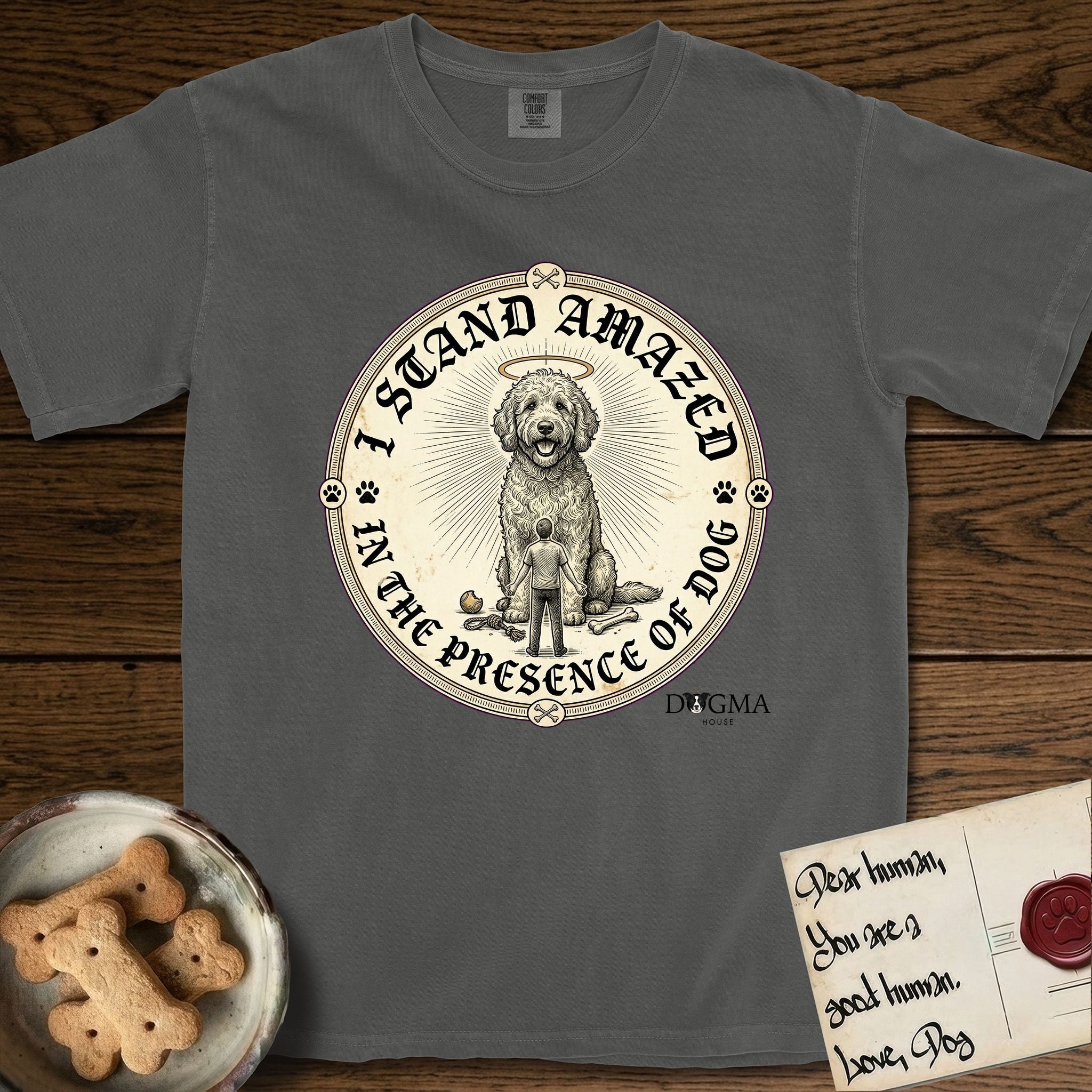 I Stand Amazed in the Presence Goldendoodle T-Shirt flat lay in Pepper, featuring a vintage engraving medallion of a haloed Goldendoodle with a small devoted human gazing up from below.
