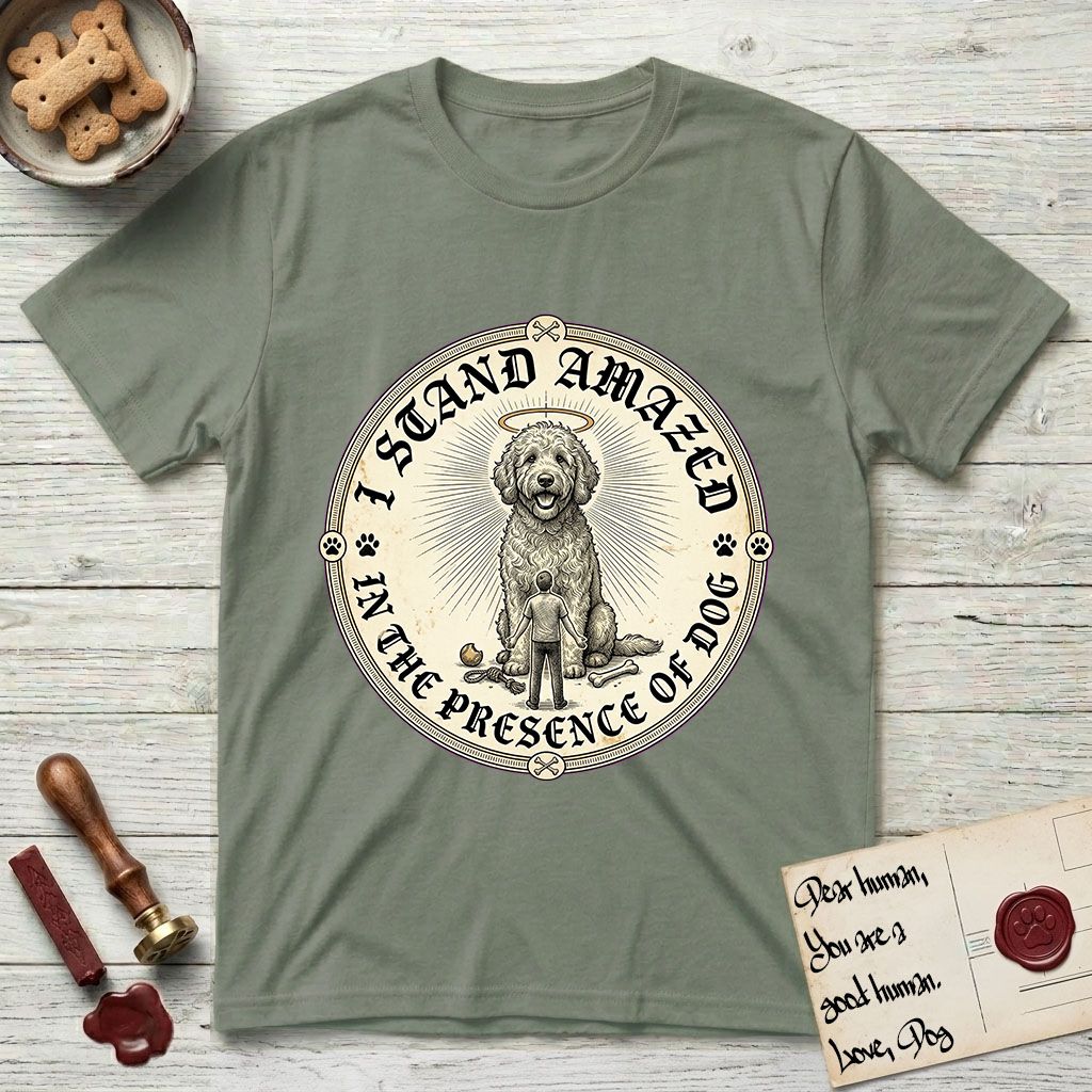 I Stand Amazed in the Presence Goldendoodle T-Shirt flat lay in Sage, featuring a vintage engraving medallion of a haloed Goldendoodle with a small devoted human gazing up from below.