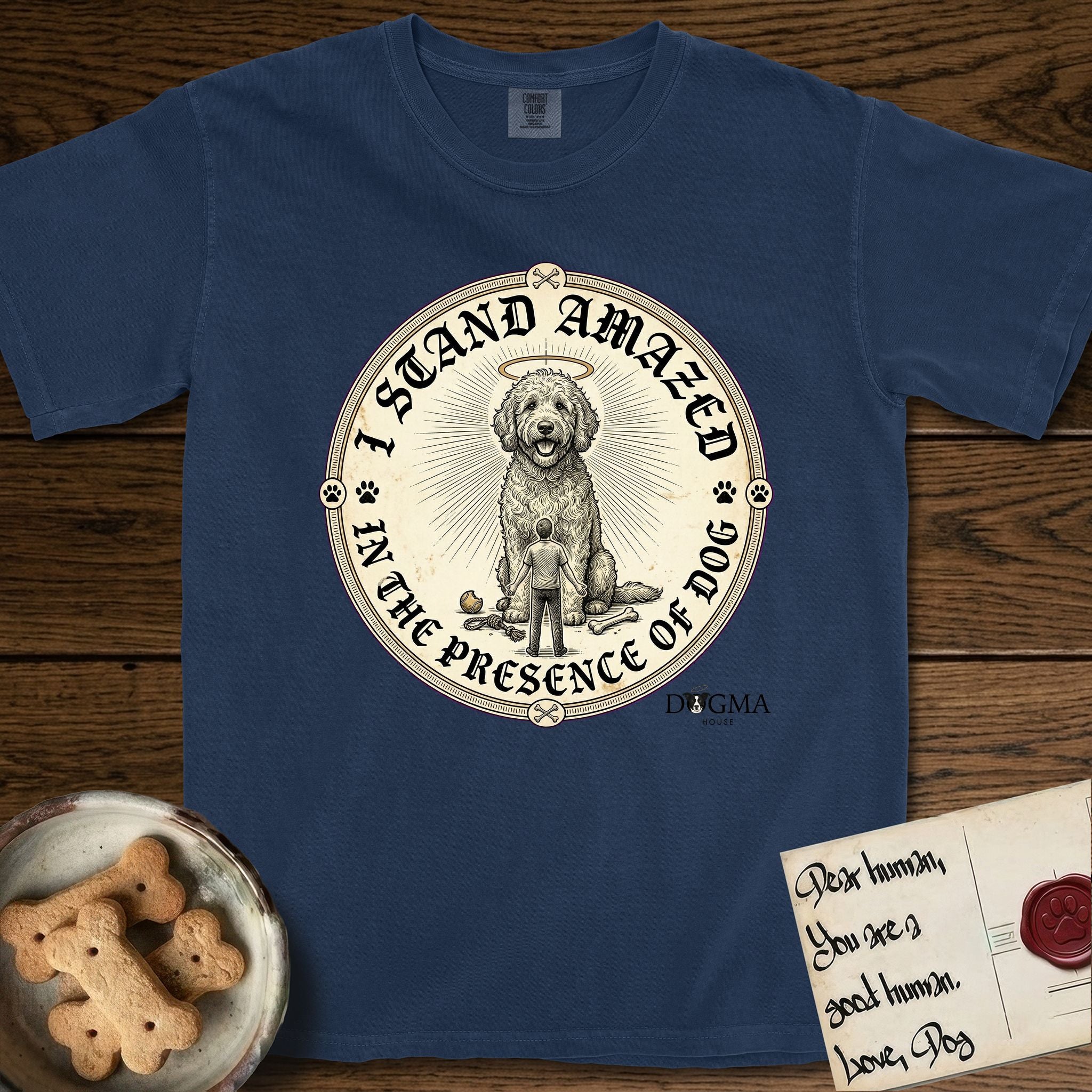 I Stand Amazed in the Presence Goldendoodle T-Shirt flat lay in True Navy, featuring a vintage engraving medallion of a haloed Goldendoodle with a small devoted human gazing up from below.