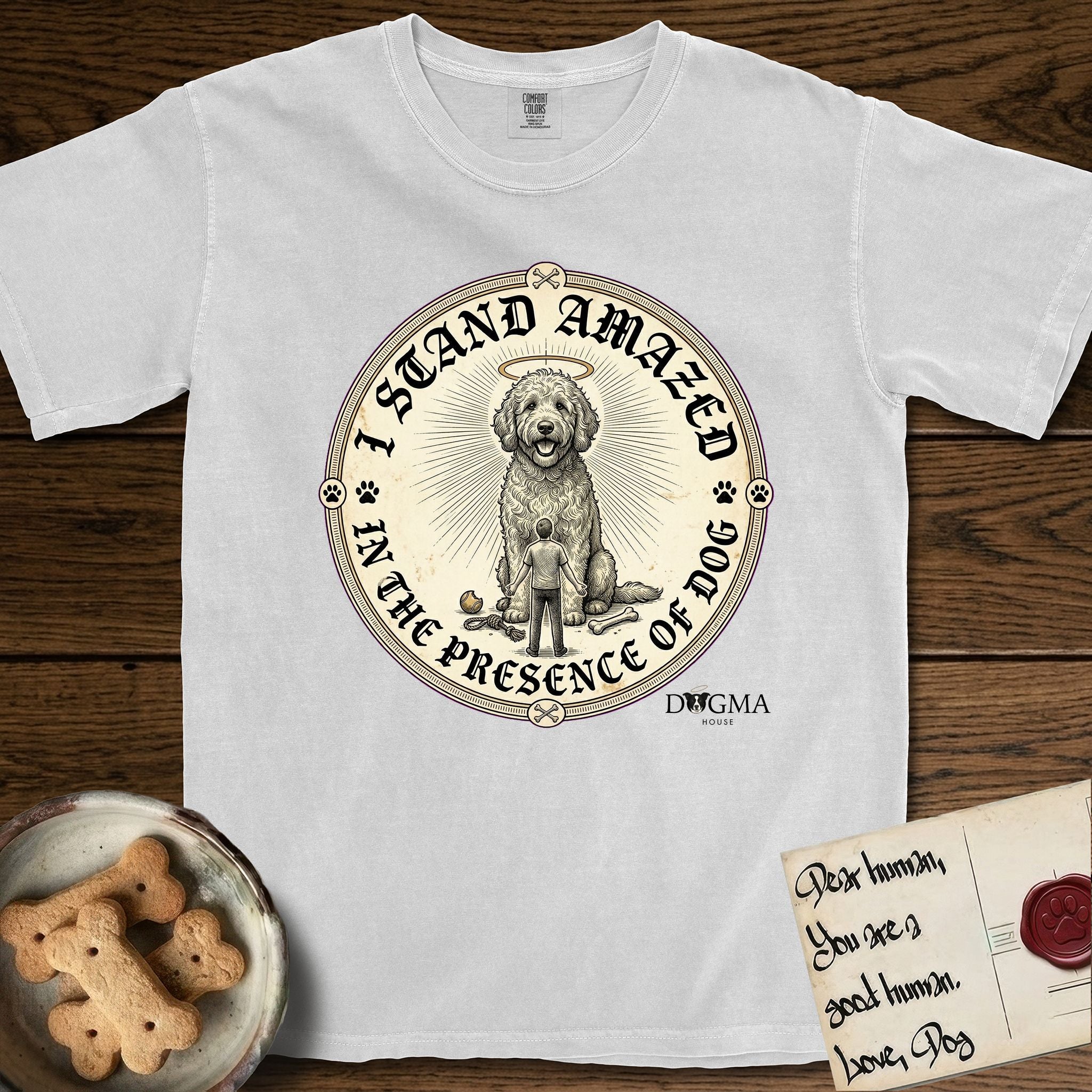 I Stand Amazed in the Presence Goldendoodle T-Shirt flat lay in White, featuring a vintage engraving medallion of a haloed Goldendoodle with a small devoted human gazing up from below.