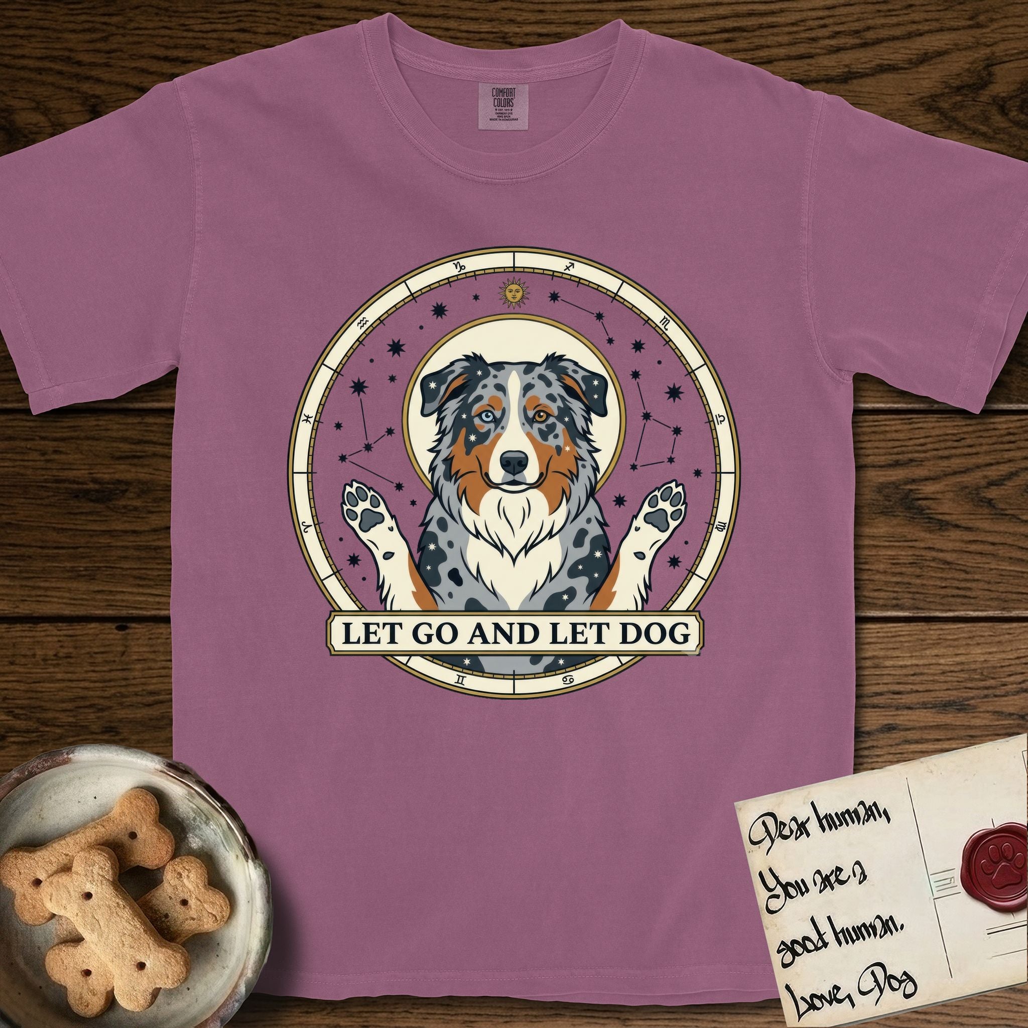 Let Go and Let Dog Australian Shepherd T-Shirt flat lay in Berry, featuring an antique celestial star chart with a haloed blue merle Australian Shepherd at the center, paws raised, stars scattered through her coat.
