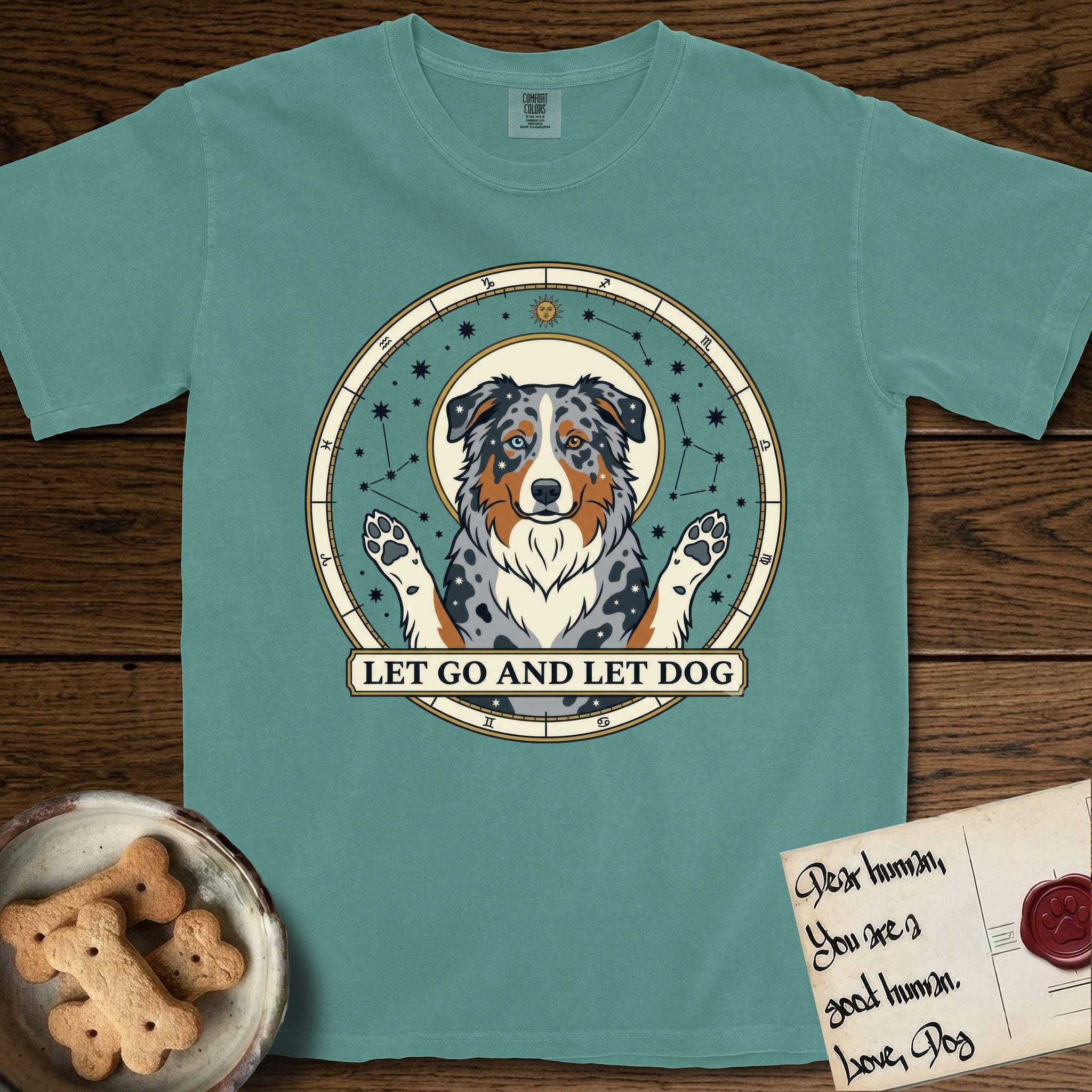 Let Go and Let Dog Australian Shepherd T-Shirt flat lay in Blue Spruce, featuring an antique celestial star chart with a haloed blue merle Australian Shepherd at the center, paws raised, stars scattered through her coat.