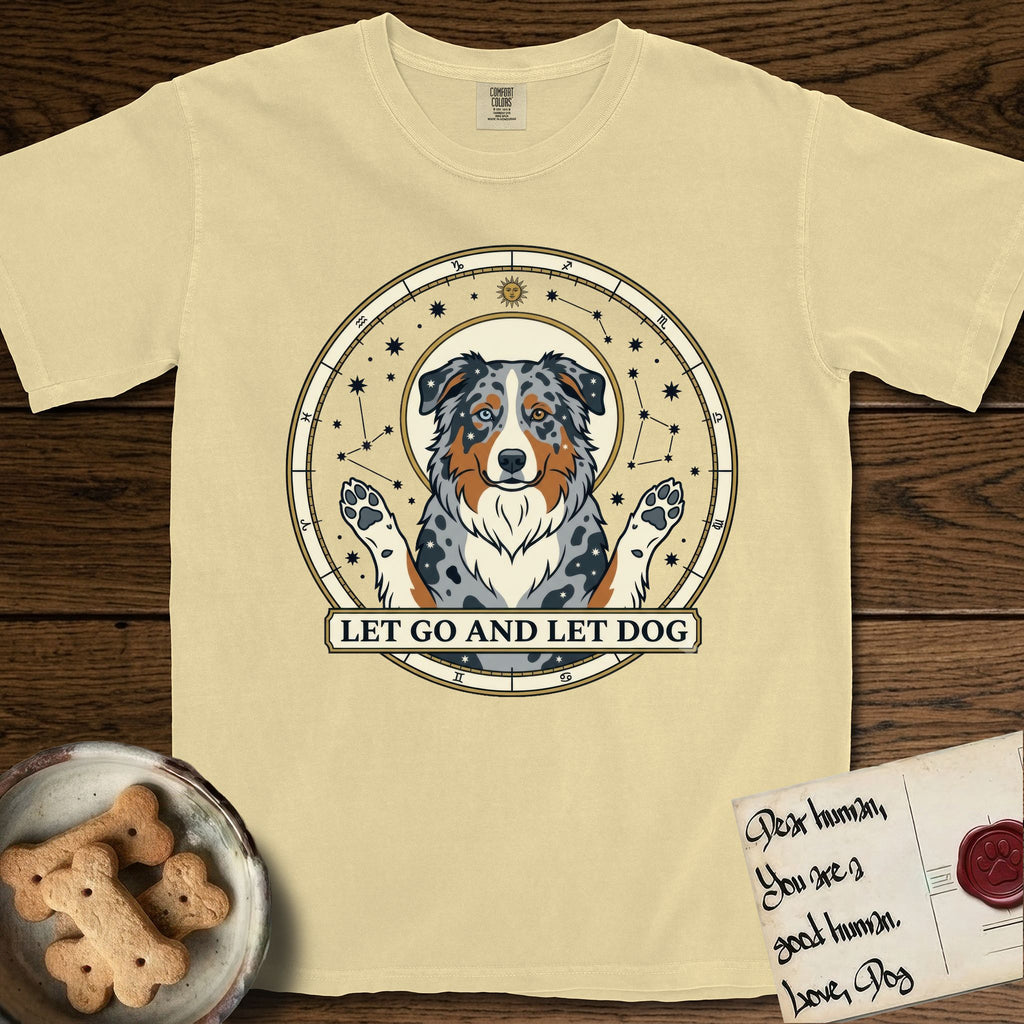 Let Go and Let Dog Australian Shepherd T-Shirt flat lay in Butter, featuring an antique celestial star chart with a haloed blue merle Australian Shepherd at the center, paws raised, stars scattered through her coat.