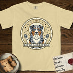 Let Go and Let Dog Australian Shepherd T-Shirt flat lay in Butter, featuring an antique celestial star chart with a haloed blue merle Australian Shepherd at the center, paws raised, stars scattered through her coat.