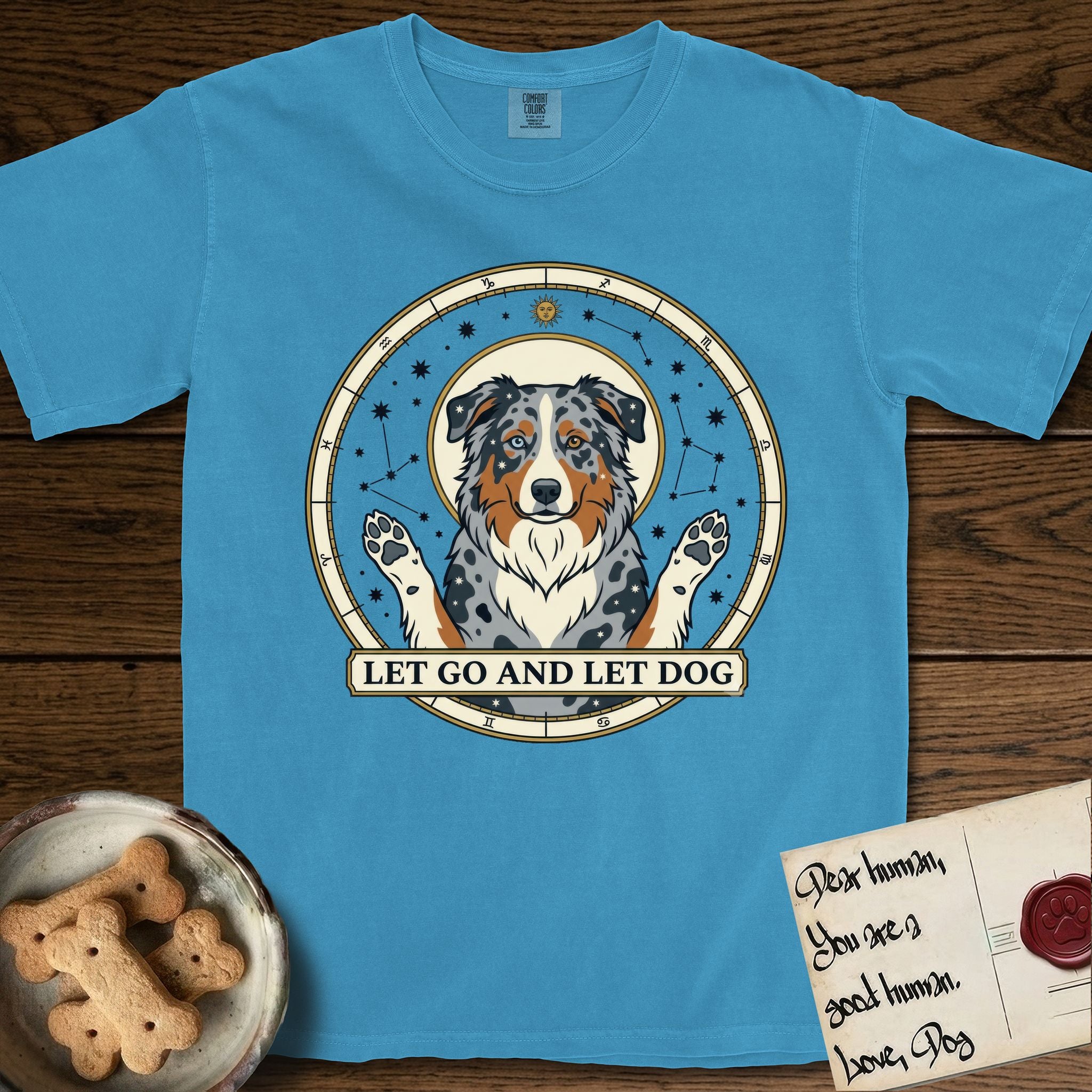 Let Go and Let Dog Australian Shepherd T-Shirt flat lay in Royal Caribe, featuring an antique celestial star chart with a haloed blue merle Australian Shepherd at the center, paws raised, stars scattered through her coat.