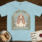 Let Go and Let Dog Basset Hound T-Shirt flat lay in Chambray, featuring an Art Nouveau botanical illustration of a haloed Basset Hound with paws raised in blessing.