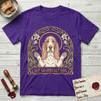 Let Go and Let Dog Basset Hound T-Shirt flat lay in Purple, featuring an Art Nouveau botanical illustration of a haloed Basset Hound with paws raised in blessing.