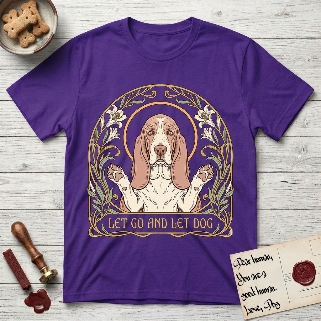 Let Go and Let Dog Basset Hound T-Shirt flat lay in Purple, featuring an Art Nouveau botanical illustration of a haloed Basset Hound with paws raised in blessing.