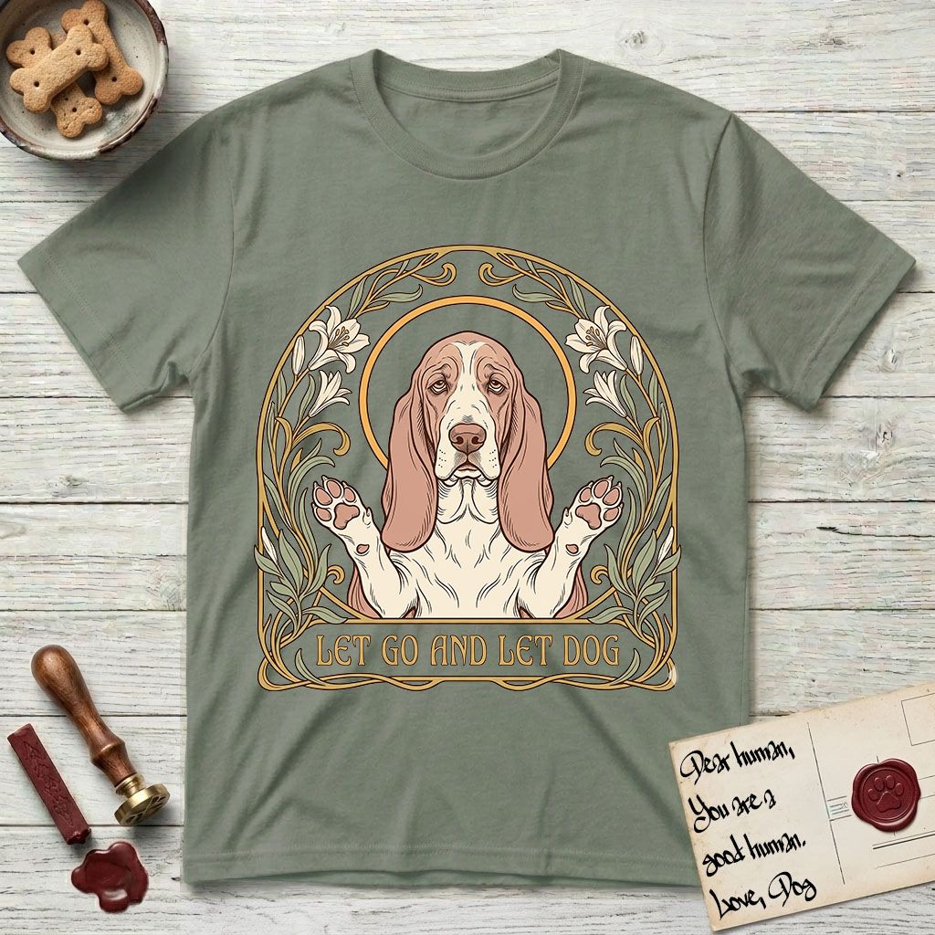 Let Go and Let Dog Basset Hound T-Shirt flat lay in Sage, featuring an Art Nouveau botanical illustration of a haloed Basset Hound with paws raised in blessing.