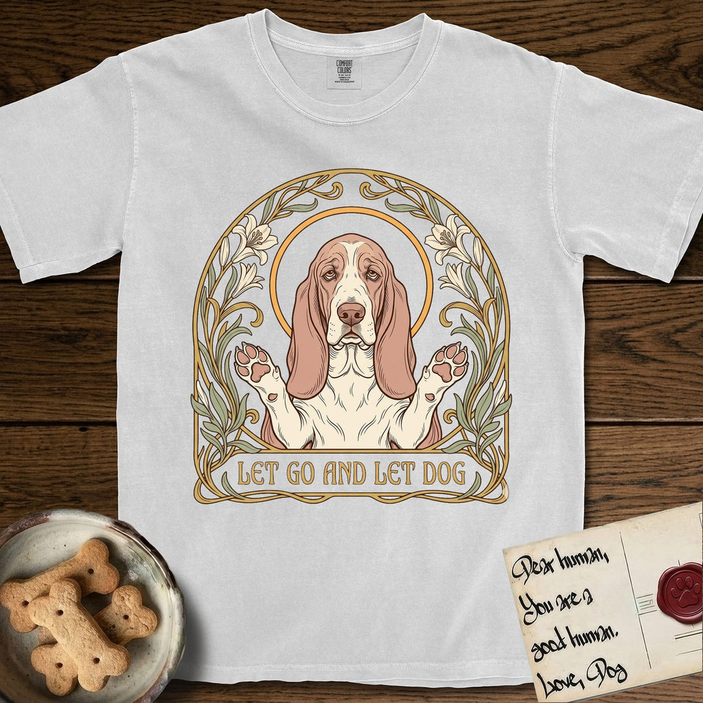 Let Go and Let Dog Basset Hound T-Shirt flat lay in White, featuring an Art Nouveau botanical illustration of a haloed Basset Hound with paws raised in blessing.